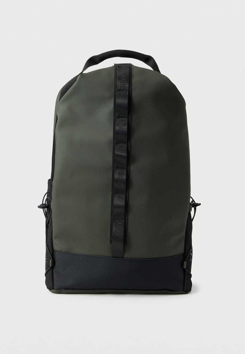 Σκούρο πράσινο και μαύρο σακίδιο με κάθετο μαύρο ιμάντα και δίχτυ στους πλαϊνούς χώρους, εμφανίζεται μπροστά σε απλό ανοιχτό φόντο.