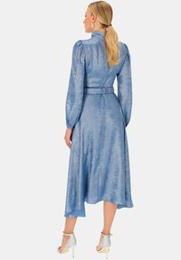 Niebieska midi sukienka z bufiastymi rękawami, wysokim kołnierzem i paskiem w talii; wykonana z teksturowanej, połyskującej tkaniny.