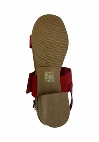 Sandal rojo con suela plana y texturizada de color marrón. Presenta una correa ancha y una hebilla metálica. Incluye símbolos de cuidado y la talla 37 en la suela.