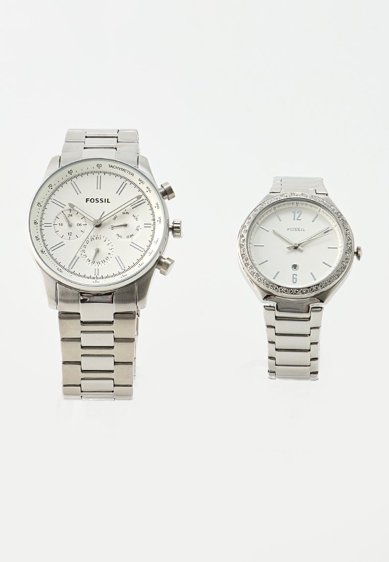 Montres en acier inoxydable argentées de Fossil ; à gauche, un design chronographe avec des sous-cadrans, tandis qu'à droite, une lunette ornée de cristaux.