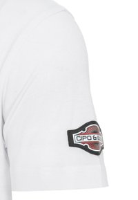 Weißes T-Shirt mit kurzen Ärmeln, das auf dem Oberarm einen schwarzen und roten Stoffpatch mit dem Text "CIPO & BAXX" zeigt. Glatte Baumwolltextur.