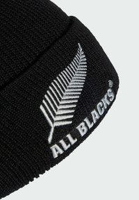Black knit beanie with a textured finish. Features white embroidered fern logo and "ALL BLACKS" text on the folded cuff.