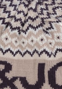 Bonnet en tricot avec une base beige, présentant des motifs en zigzag et en diamant violets. Le matériau en laine texturé ajoute chaleur et détail.