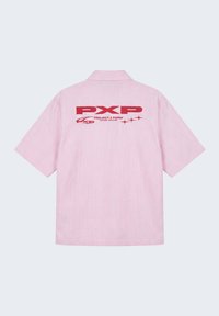 Chemise à manches courtes à fines rayures roses et blanches avec col, avec grand texte rouge "PXP Project X Paris" et étoiles dans le dos.