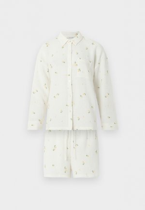 Valkoinen nappikiinnitteinen pyjamapuku pitkillä hihoilla ja shortseilla, jossa on hienovarainen keltavihreä kukkakuosi ja rintatasku.