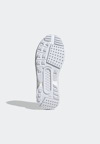 Vit sneakersula med mönstrad textur, cirkulära nubb och greppvänliga områden, visad mot en neutral ljusgrå bakgrund.