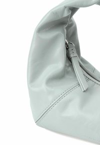 Borsa a spalla in pelle grigia chiara con una silhouette curva, texture morbida e chiusura con zip dotata di un lungo brillantino in pelle e cuciture minimali.