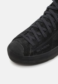 Schwarzer Wildlederschuh zum Klettern mit einer Gummispitze, Schnürdesign und strukturiertem Obermaterial. Verfügt über Logodetails und eine strapazierfähige Sohle.
