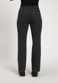 Pantalones vaqueros de mezclilla gris oscuro con pierna recta, cinturilla elástica y dos bolsillos traseros con detalles de costura decorativa.
