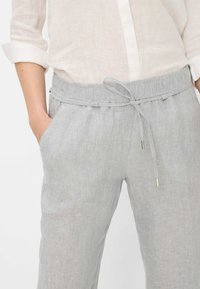 Lichtgrijze linnen broek met een elastische tailleband en een trekkoord. Voorzien van zijzakken en een gladde, gestructureerde stof. Casual snit.