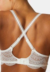 Vitt spetsbehå med en delikat blomsterdesign, racerback-stil, justerbara axelband och hak-och-ögonknäppning bak.