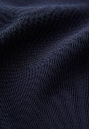 Tmavě modrá látka s texturovaným, tkaným povrchem. Materiál vypadá mírně zmačkaně, což ukazuje na jeho ohebnou povahu a bohatou barvu.