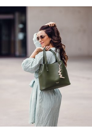 Olivgrüne Ledertasche mit glatter Textur, ausgestattet mit einem dekorativen silbernen Blitz-Anhänger und robusten Schultergurten.