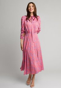 Różowa sukienka w kwiatowy wzór, z długimi bufkami, wiązaniem przy szyi oraz swobodnym fasonem. Gładki materiał o miękkiej strukturze.