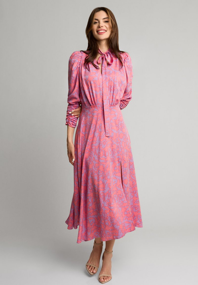 Różowa sukienka w kwiatowy wzór, z długimi bufkami, wiązaniem przy szyi oraz swobodnym fasonem. Gładki materiał o miękkiej strukturze.