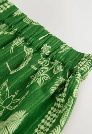 Tessuto verde con cintura elasticizzata, caratterizzato da motivi botanici e geometrici bianchi. Texturizzato con una leggera lucentezza e morbida caduta.