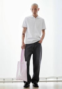 Witte poloshirt, donkergrijze jeans met brede pijpen, zwarte schoenen en een lichtroze tas met een wit logo. Soepele texturen en eenvoudig ontwerp.