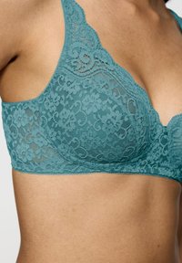 Kanten bh in teal, met een V-halsontwerp, bloempatroon, verstelbare bandjes en gegolfde randen voor extra textuur en detail.