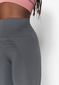 Höga grå leggings i ribbat tyg, med en sömlös sidopaneldesign och en mjuk yta.