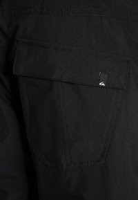 Sorte denim shorts har en klaplomme med et logo-tag, lige snit, struktureret stof og kontrasterende syninger.