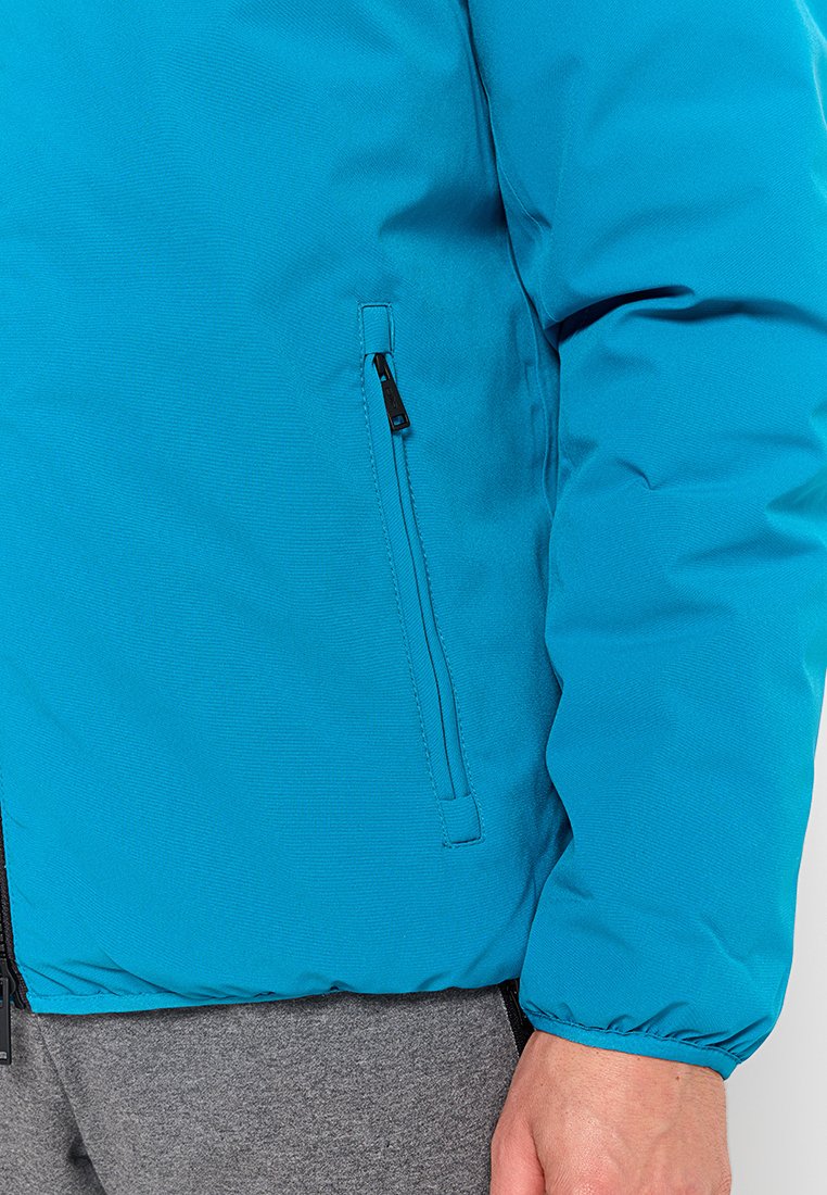 Giacca puffer teal con una texture liscia, dotata di una tasca laterale con zip e polsini elasticizzati per una vestibilità aderente. Design leggero e isolato.