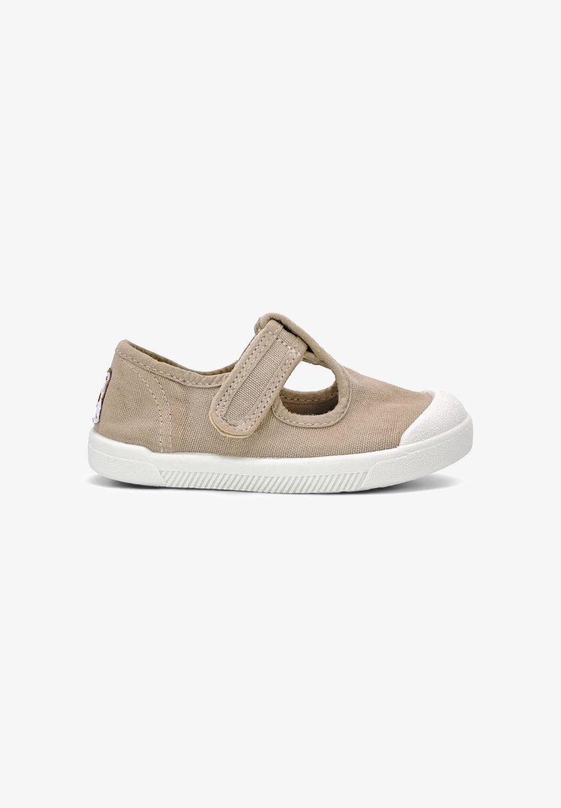 Chaussure beige pour tout-petit avec semelle en caoutchouc blanche et embout, avec une seule bride Velcro réglable sur le dessus.