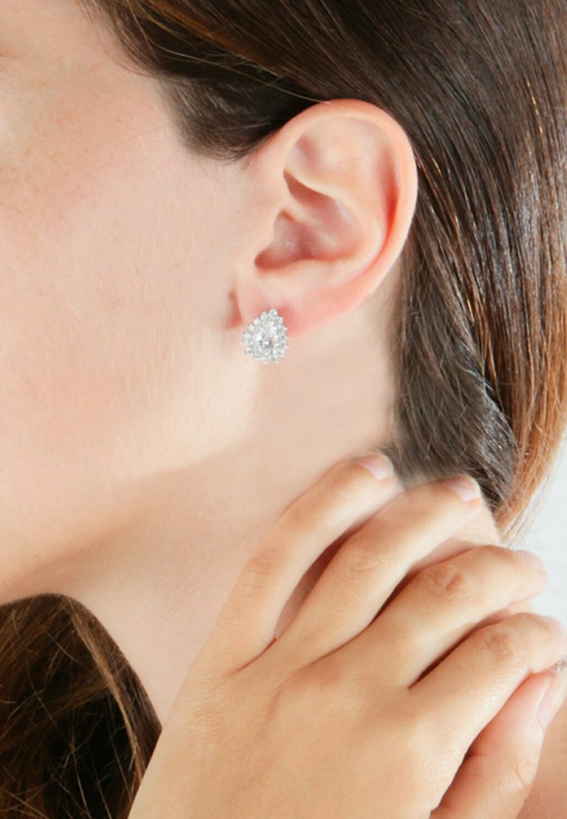 Orecchini in tonalità argento a forma di pera, circondati da piccole pietre rotonde, con una finitura lucida e dettagli testurizzati.