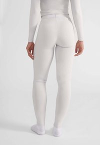 Leggings blancos con una textura suave, diseño ajustado, cintura alta y corte a la altura del tobillo. La tela es elástica y se ajusta al cuerpo.