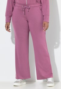 Fialové široké tepláky s elastickým pasem a šňůrkou. Měkká textura látky, doplněná o třpytivé bílé tenisky.