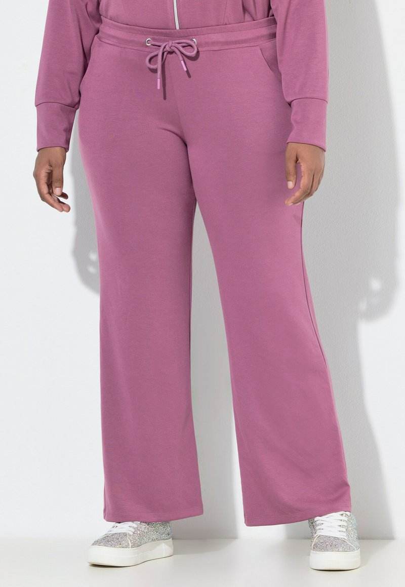 Fialové široké tepláky s elastickým pasem a šňůrkou. Měkká textura látky, doplněná o třpytivé bílé tenisky.