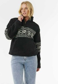 Pullover in pile nero con zip a quarto, caratterizzato da un motivo astratto bianco sul petto e sulle maniche. Tessuto morbido e vestibilità rilassata.
