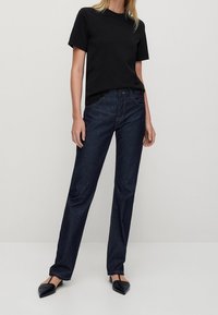 Svart t-shirt med kort ärm i kombination med mörkblå denimjeans. Jeansen har rak passform och en klassisk femficksdesign.