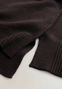 Dunkelbrauner Pullover mit weicher, gestrickter Textur, gerippten Bündchen und gespaltenem Saum, der Komfort und Bewegungsfreiheit erhöht.