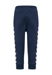 Mörkblå träningsbyxor med ribbad midja, tapered passform och kontrasterande vita chevronränder på sidorna. Slät tygtextur genom hela byxorna.