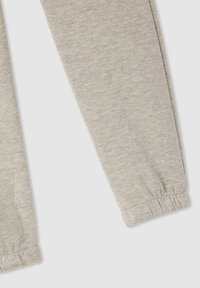Jasnoszare spodnie dresowe wykonane z miękkiej mieszanki bawełny, wyposażone w elastyczny pas i ściągacze dla luźnego dopasowania. Gładka faktura bez wzorów.