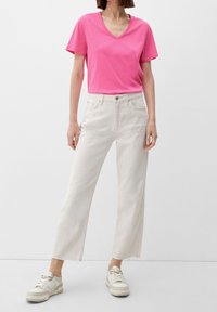 Fuchsia bomull V-hals t-shirt i kombination med off-white högmidjade vida jeans och beige sneakers. Jeansen har detaljer med fransar i fållarna.