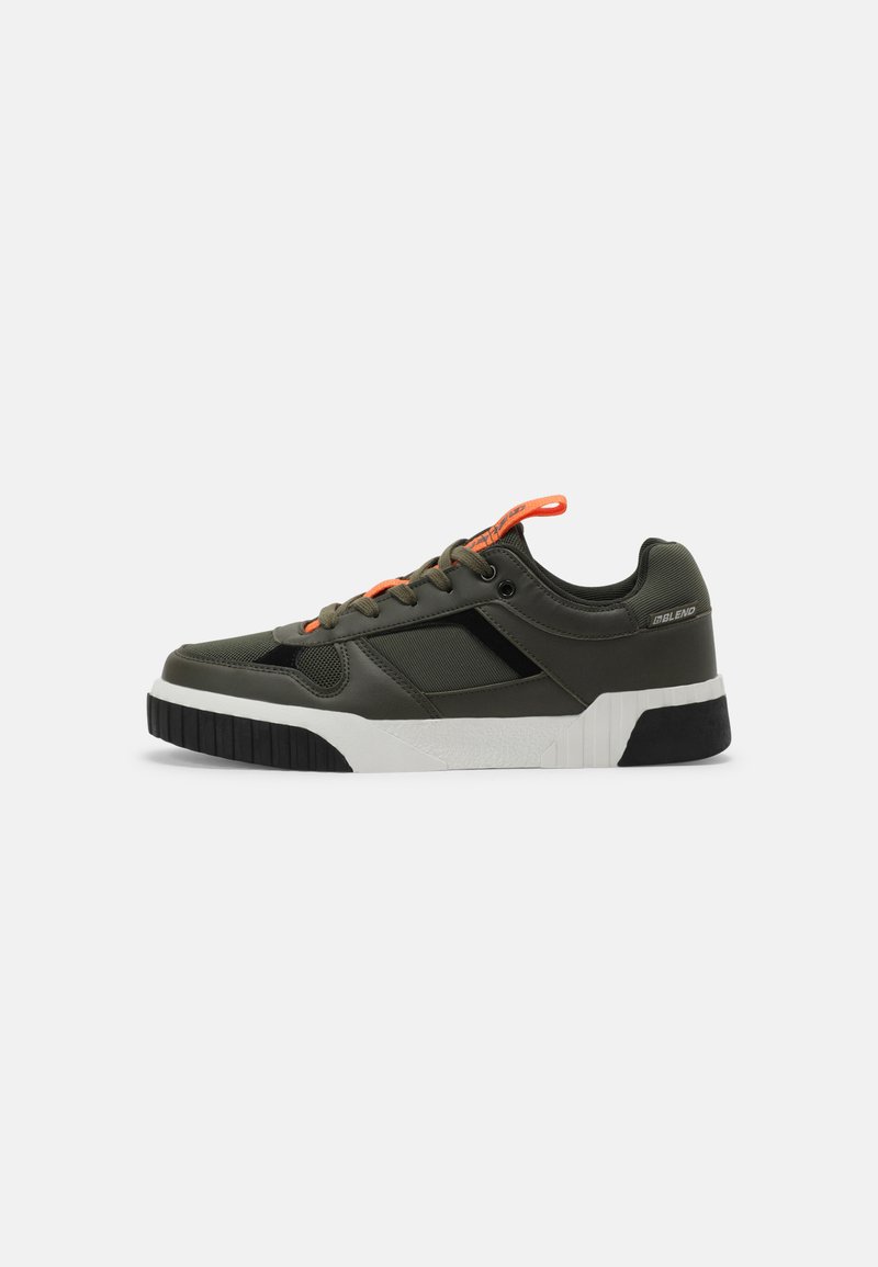 Green sneakers with a mix of smooth and textured materials, featuring orange laces, a white midsole, and a black rubber outsole.