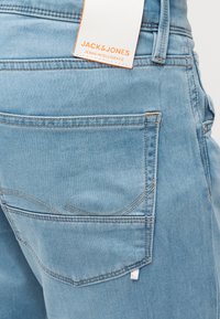 Πίσω τσέπη φωτεινού μπλε τζιν με ετικέτα Jack & Jones ραμμένη στη μέση του παντελονιού.