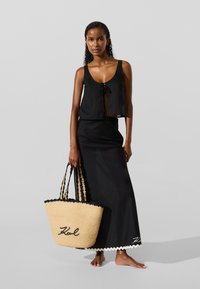 Juodas trumpas viršus su raišteliu, derinamas su ilga juoda sijonu, turinčiu banguotą kraštą. Laikoma didelė pintinė rankinė su juodais akcentais.