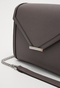 Borsa a spalla in ecopelle grigia con superficie testurizzata, design geometrico, accessori in tonalità argento e tracolla a catena staccabile.