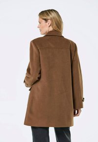 Brauner Wollmischungs-Mantel mit lässigem Schnitt, Reverskragen und langen Ärmeln. Mit Knopfdekor an den Manschetten und einem Schlitzausschnitt hinten für mehr Bewegungsfreiheit.