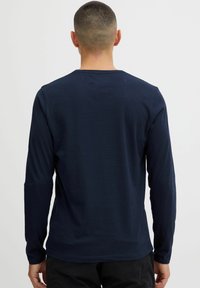 Navy long-sleeve shirt made from soft cotton, featuring a crew neck and simple design, with a smooth texture and relaxed fit.