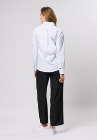 Heledat sinise triibulise kraega särk, pika varrukaga, selja voldiga, koos mustade laiade pükste ja valgete tossudega.