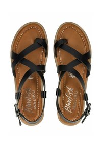 Černé veganské kožené sandály s křížovými popruhy a nastavitelnou sponou na kotníku. Hnědá texturovaná stélka s bílým prošíváním. Plochá podrážka.