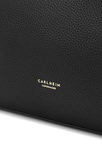 Black textured leather bag featuring a gold-embossed logo "CARLHEIM COPENHAGEN" on the front. Smooth surface with detailed grain pattern.