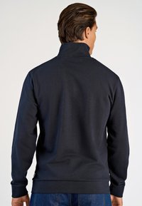Sudadera azul marino con un cuello alto, mangas largas y puños y dobladillo acanalados. Fabricada con un tejido suave y liso con un diseño minimalista.