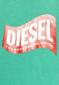 Zelené bavlněné tričko s velkým červeným a bílým logem "DIESEL", zakřivený design a pod tím nápis "PRO ÚSPĚŠNÝ ŽIVOT".