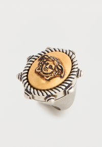 Anillo de plata con una pieza central ovalada de oro que presenta una cabeza de Medusa grabada y un diseño de cuerda retorcida alrededor del borde.