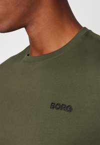 Olivengrøn bomulds t-shirt med rund hals, udstyret med sort "BORG" broderi på brystet og glat, ikke-struktureret stof.