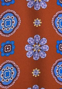 Tissu couleur rouille avec des motifs floraux et circulaires bleus et violets espacés uniformément sur toute la surface.
